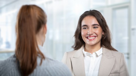 Zwei Frauen unterhalten sich in einem hellen Büro.